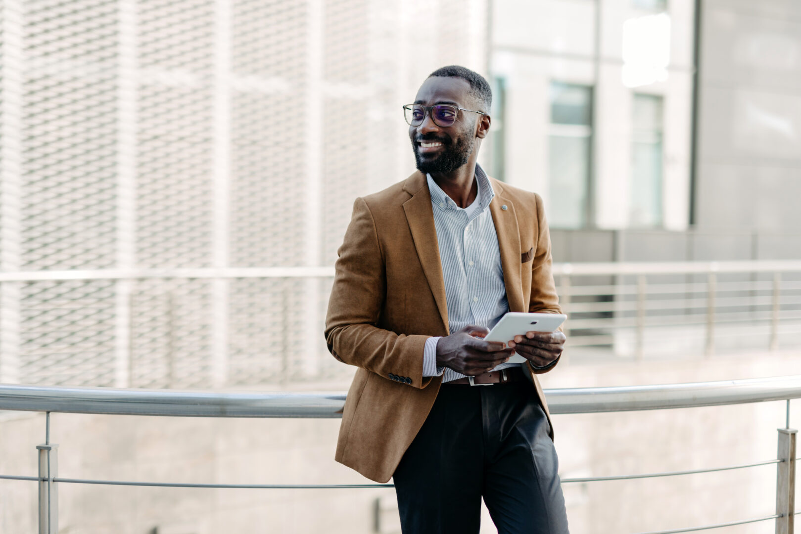 Man leaning on railing with a tablet outdoors